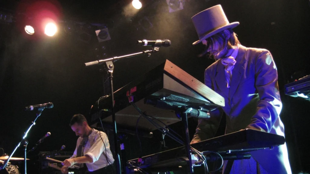 Royksopp performing live at keyboards under stage lighting