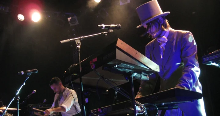 Royksopp performing live at keyboards under stage lighting